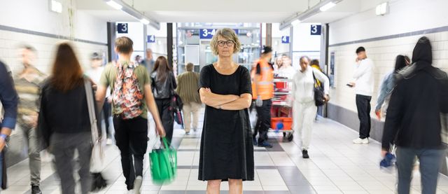 Susanne Menge mit verschränkten Armen vor einem belebten Durchgang im Oldenburger Hauptbahnhof